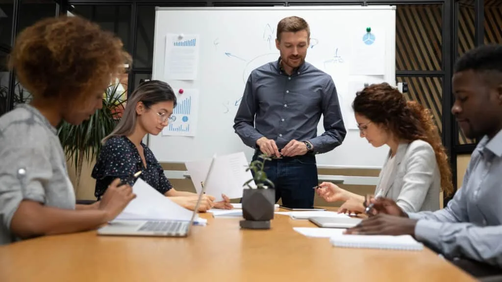 Multiethnic staff take part in a website SEO audit led by manager in a boardroom.