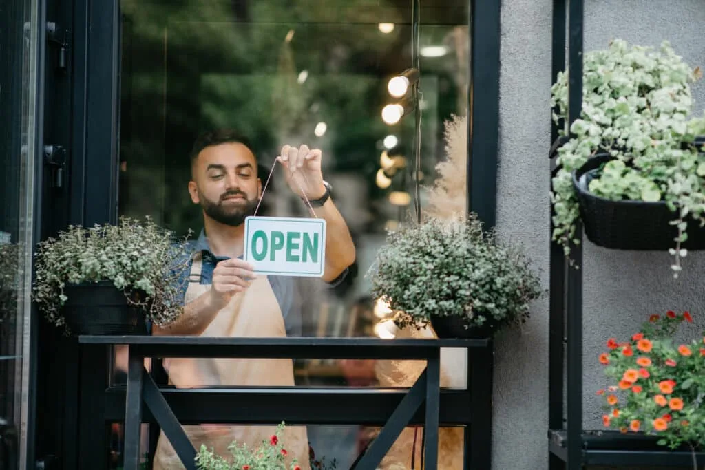 Male business owner preparing storefront for customers after using a local SEO checklist.