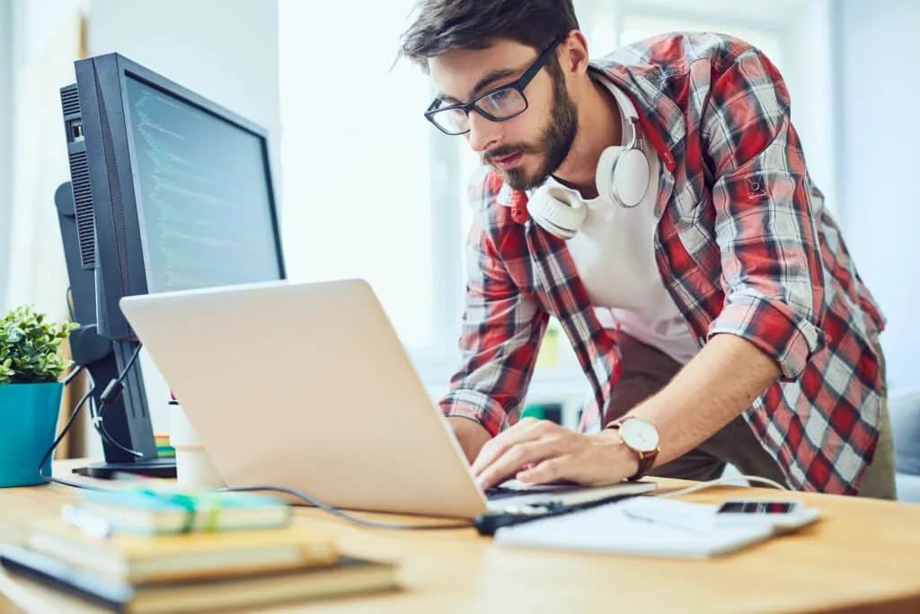 Young software developer standing at his desk and working on a technical SEO checklist.